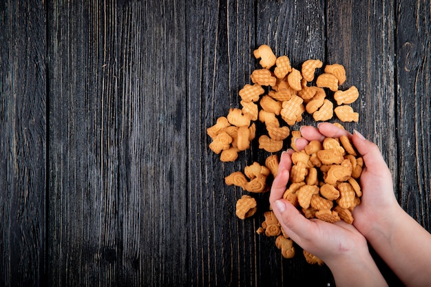 Free photo top view copy space woman holds cookies on a black wooden background