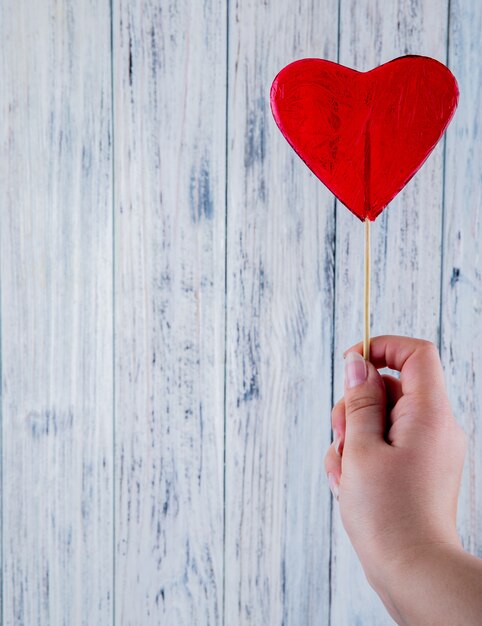 Top view copy space woman holds lollipop in the shape of a red heart