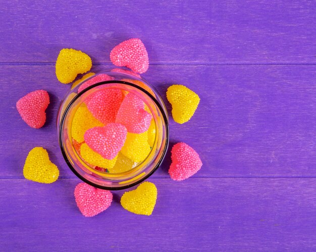 Top view copy space yellow and pink marmalade in the shape of a heart in a jar on a purple background