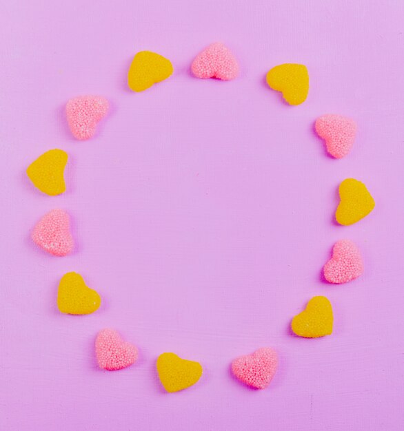 Top view copy space yellow and pink marmalade in the shape of a heart on a light pink background