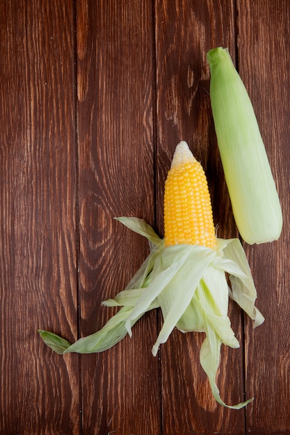 Free photo top view of corn cobs with shell on wood