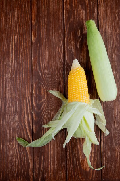 Top view of corn cobs with shell on wood