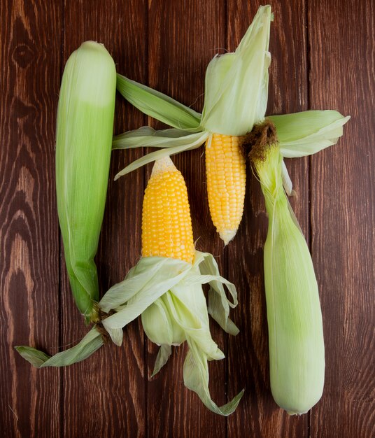 Top view of corn cobs with shell on wood