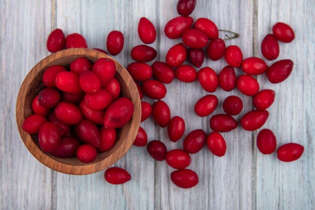 Top view of cornel berries in bowl and on wooden background