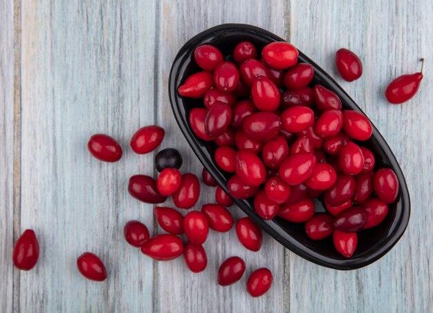 Top view of cornel berries in oblong bowl and on wooden background