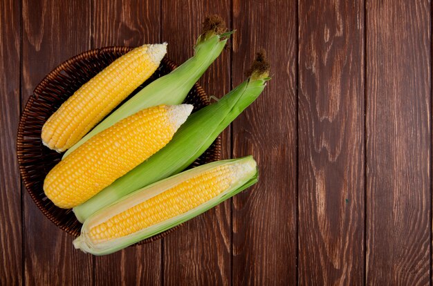 Top view of corns in basket on wood with copy space