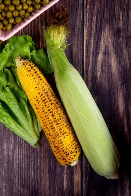 Top view of corns with lettuce on wooden surface