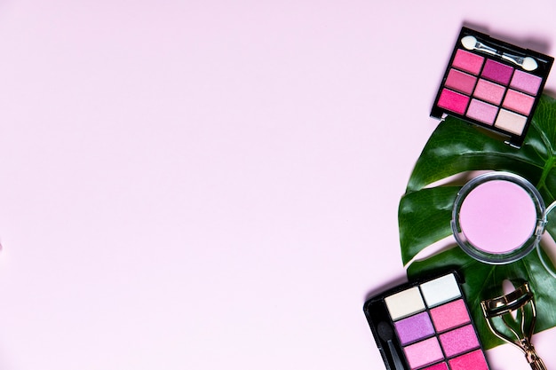 Top view on cosmetics on pink background with copy space