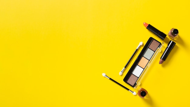 Top view of cosmetics on yellow background with copy space
