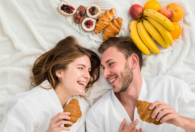 Top view of coupe in bed with fruits and croissants