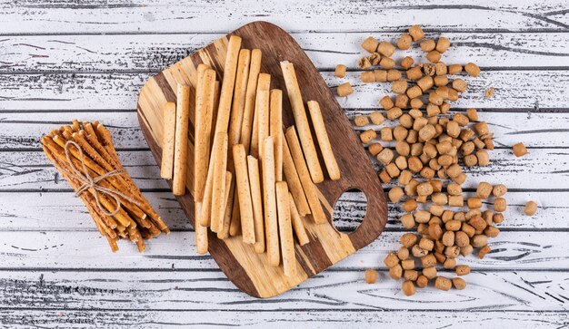 Top view of crackers on cutting board on white wooden  horizontal