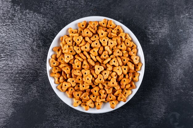 Top view crackers in white bowl on black stone  horizontal