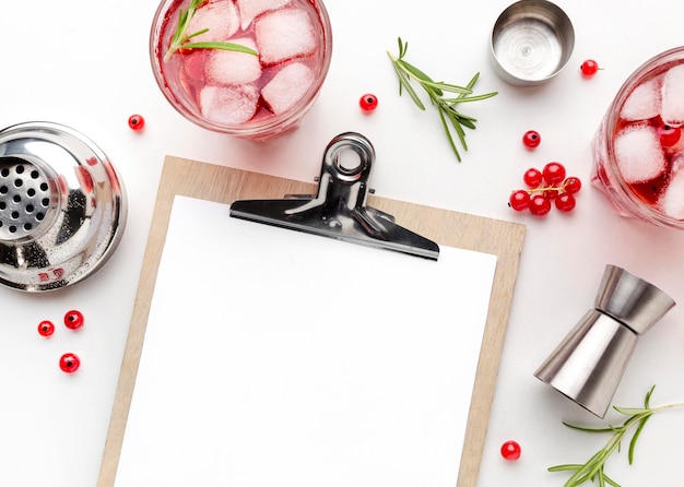 Top view cranberry vodka with shaker and blank clipboard