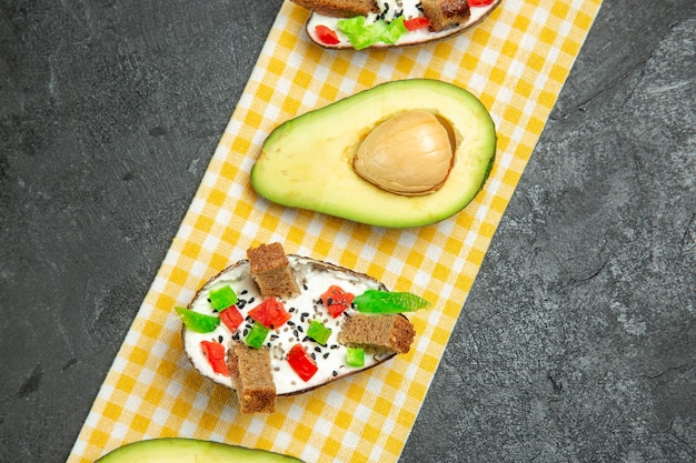 Top view of creamy avocados with fresh avocado on grey surface