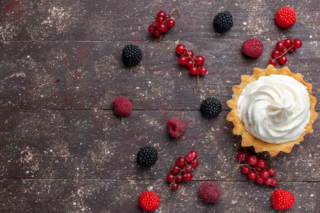 갈색 바닥 베리 과일 크림 베이킹 비스킷 전체에 퍼져있는 차별화 된 딸기와 함께 크림 맛있는 케이크의 상위 뷰