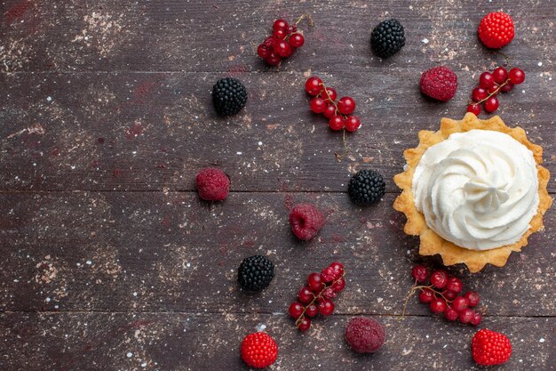 Top view of creamy delicious cake along with differented berries spread all over the brown floor berry fruit cream bake biscuit