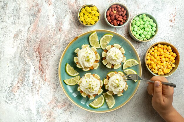 Вид сверху сливочно-вкусные торты с дольками лимона на белой поверхности торт бисквитное печенье крем чай сладкий