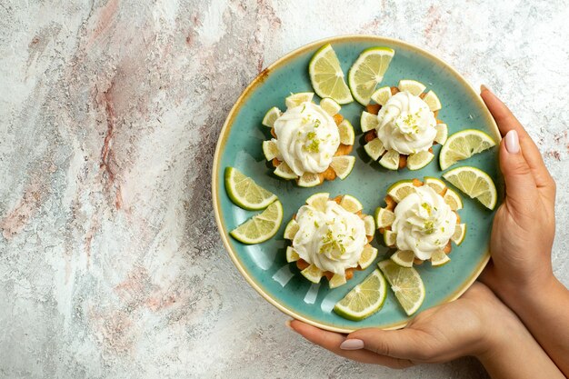 Top view creamy delicious cakes with lemon slices on white surface cake biscuit cookie cream tea sweet