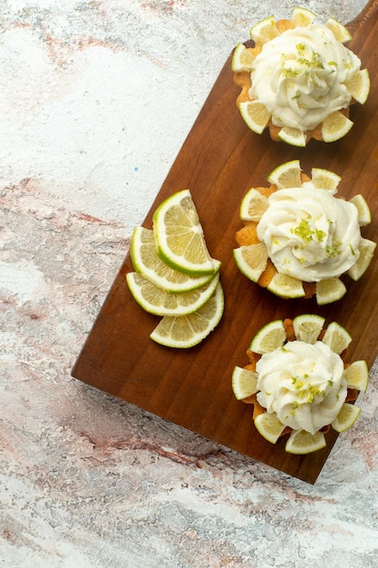 Foto gratuita vista dall'alto deliziose torte cremose con fette di limone su superficie bianca torta biscotto biscotto crema di tè dolce