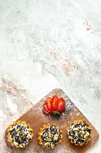 Vista dall'alto deliziose torte cremose con fragole rosse affettate su superficie bianca torta di tè biscotto crema di compleanno dolce