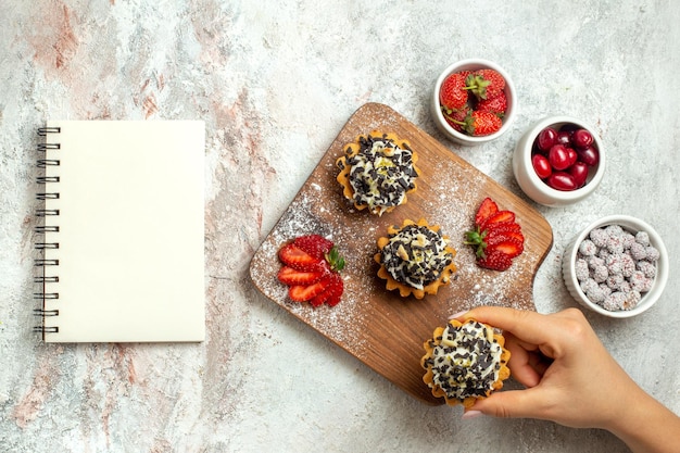 Top view creamy delicious cakes with sliced strawberries on a white surface birthday tea biscuit sweet cake cream