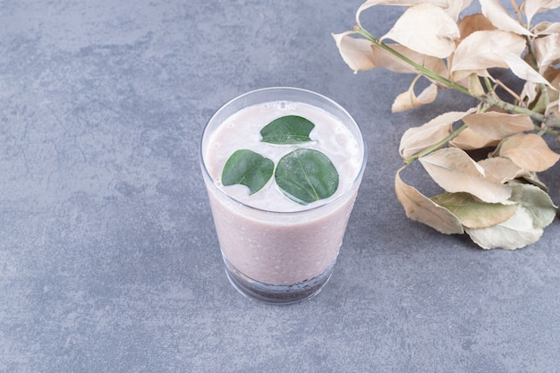 Top view of creamy milk shake with mint on grey background.