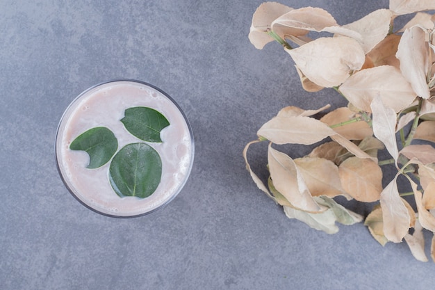 Foto gratuita vista dall'alto del frullato cremoso con foglie di menta su sfondo grigio.