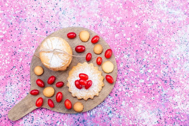 Top view of creamy sandwich cookies with red dogwoods on bright, cookie cake biscuit sweet sour fruit berry