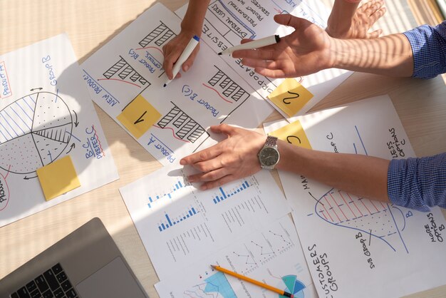Вид сверху творческой группы обсуждают бизнес-графики, нарисованные в маркерах