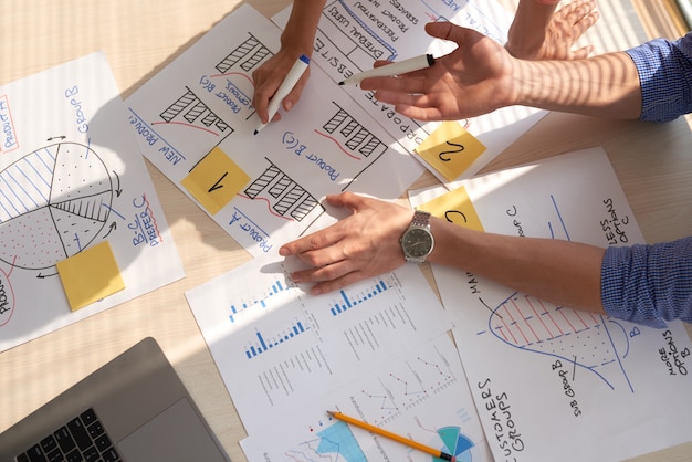 Top view of creative team discussing business graphs drawn in marker pens