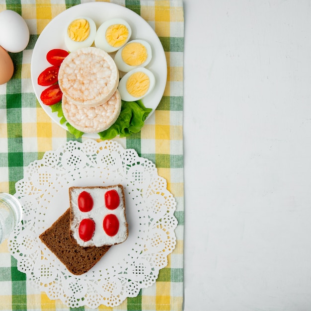 Crispbreads와 빵 조각의 상위 뷰 복사 공간 천으로 흰색 배경에 코티지 치즈로 얼룩 져