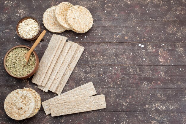 Top view crisps and crackers long and round formed with dried seasonings on wood