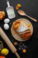 Foto gratuita vista dall'alto di croissant su sottopentola con farina di uova kumquat limone mandarino cucchiaio e mattarello su sfondo nero