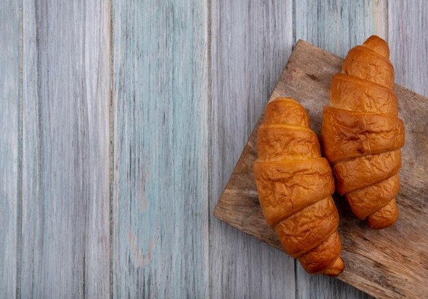Top view of croissants on cutting board on wooden background with copy space