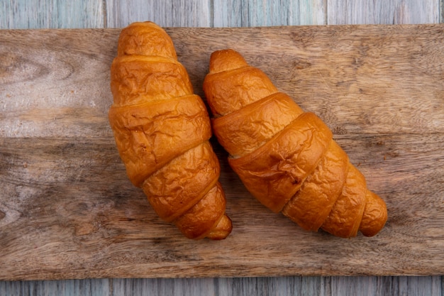 Top view of croissants on cutting board on wooden background