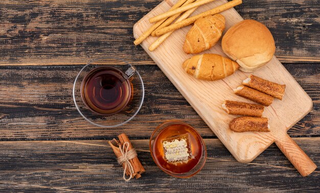 Top view of croissants with tea and honey on dark wooden surface horizontal