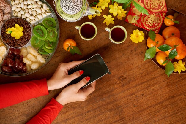 Top view of cropped hands sending Tet congratulation messages