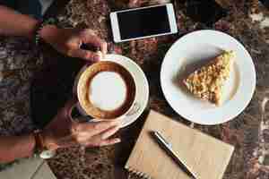 Free photo top view of cropped unrecognizable woman having coffee and dessert in the cafe