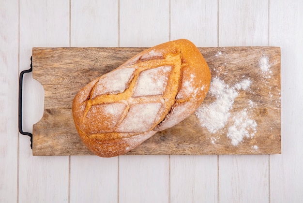 Free photo top view of crusty bread with flour on cutting board on wooden background