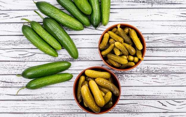 Top view cucumber pickled in bowl and fresh on white wooden  horizontal