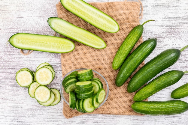 Top view cucumber sliced in glass bowl on beige linen bag on white wooden  horizontal