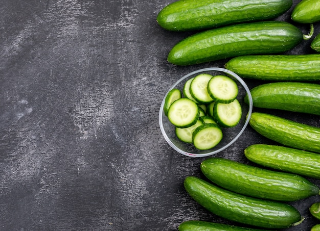 Free photo top view cucumber sliced in glass bowl with copy space on black stone  horizontal