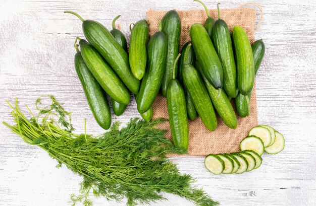 Top view cucumber sliced with dill on beige linen bag on white wooden  horizontal