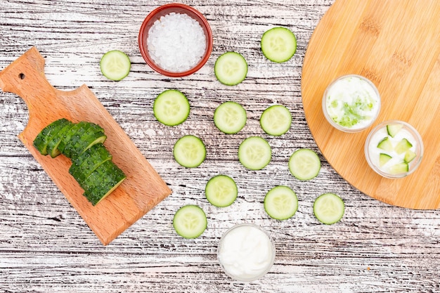 Foto gratuita cetriolo di vista superiore affettato con sale in ciotola e yogurt sul tagliere su di legno bianco