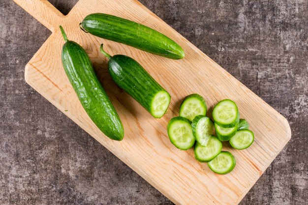 Top view cucumber sliced on wooden cutting board on brown stone  horizontal 1
