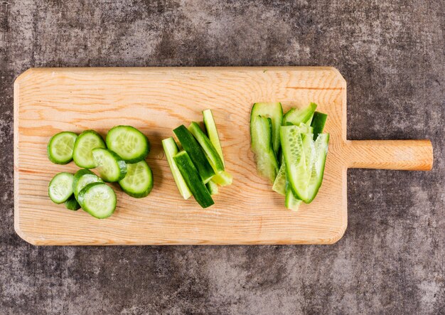 Top view cucumber sliced on wooden cutting board on brown stone  horizontal