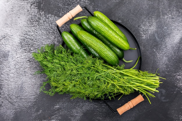 Top view cucumber with dill on black metal tray on black stone  horizontal