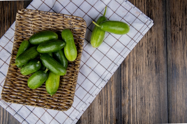 Top view of cucumbers in basket plate on cloth and wood