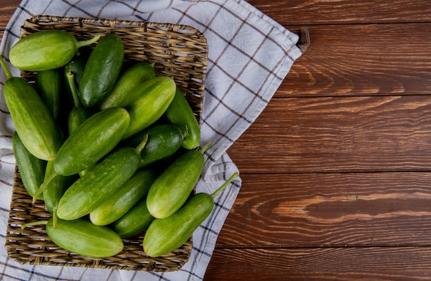 Free photo top view of cucumbers in basket plate on plaid cloth and wood with copy space