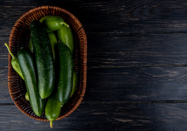 Top view of cucumbers in basket on wooden surface with copy space